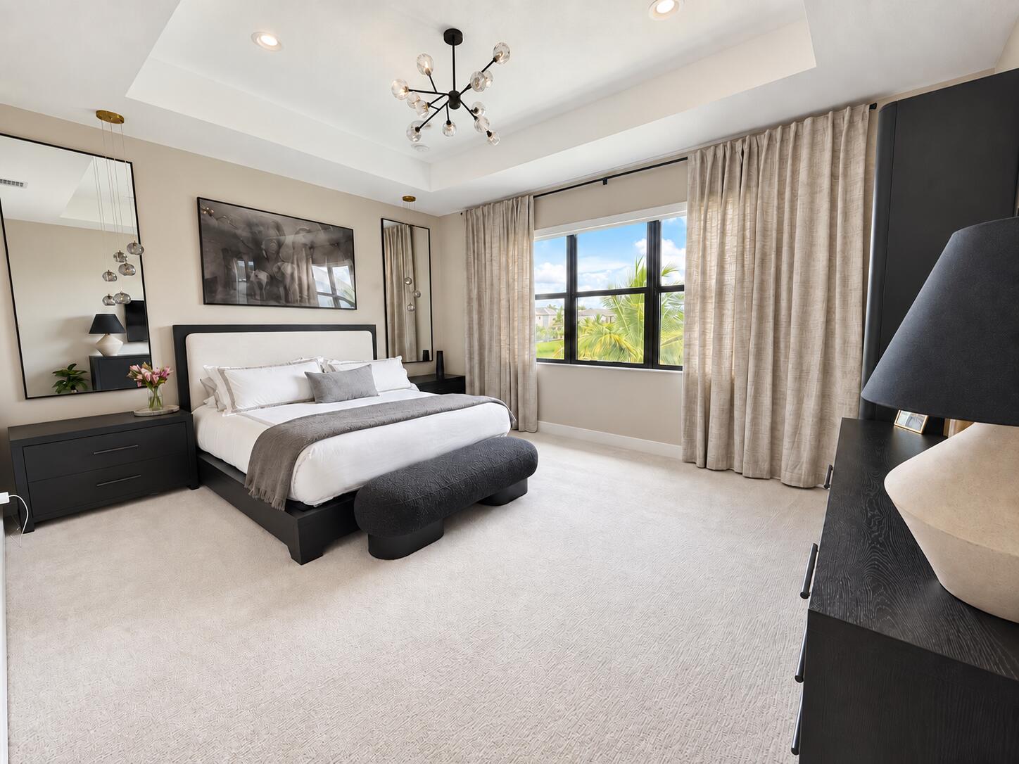 Furnished bedroom with a king-size bed, dark modern furniture, and a large window overlooking palm trees.
