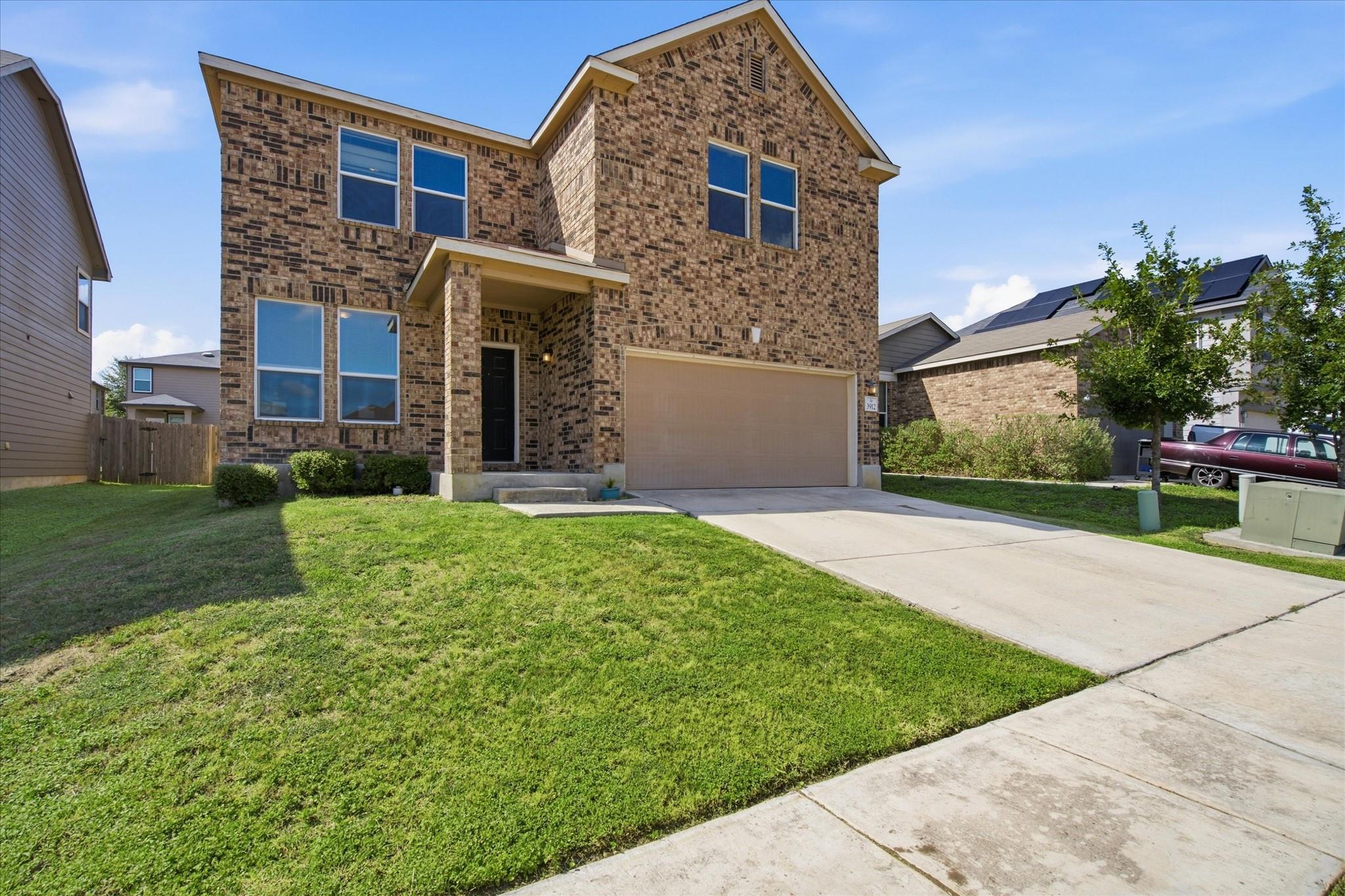 Two-story brick house with a covered entry, double garage, and broad concrete driveway.
