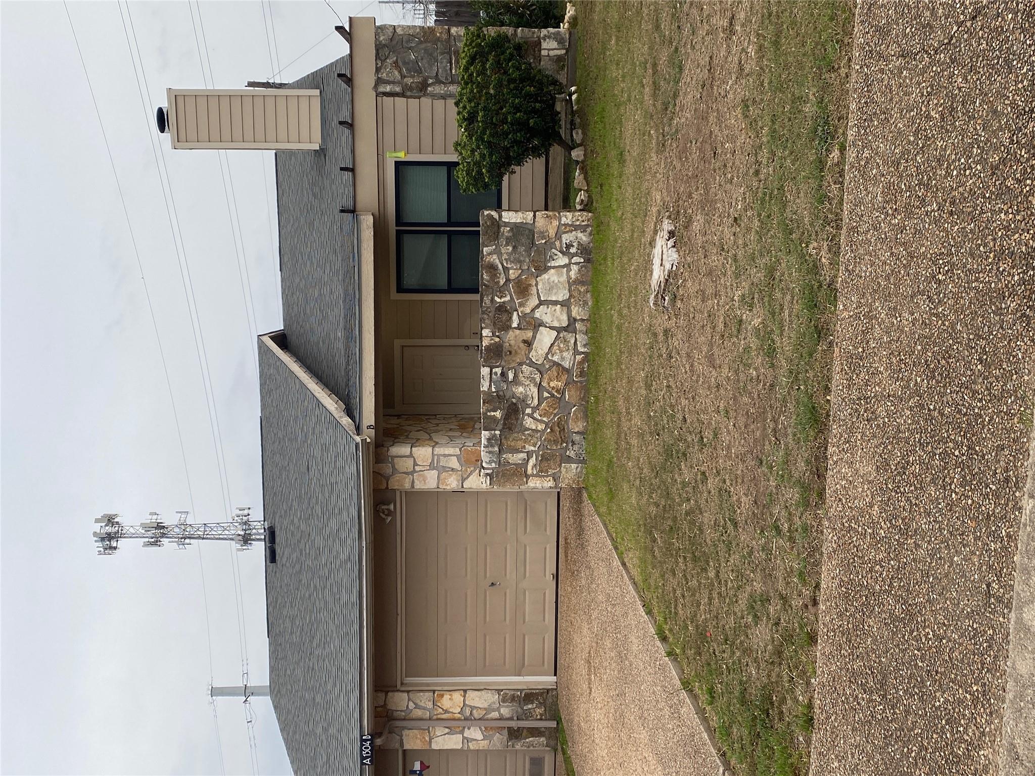 Tan single-story house with an attached garage, stone accents and a low front wall.