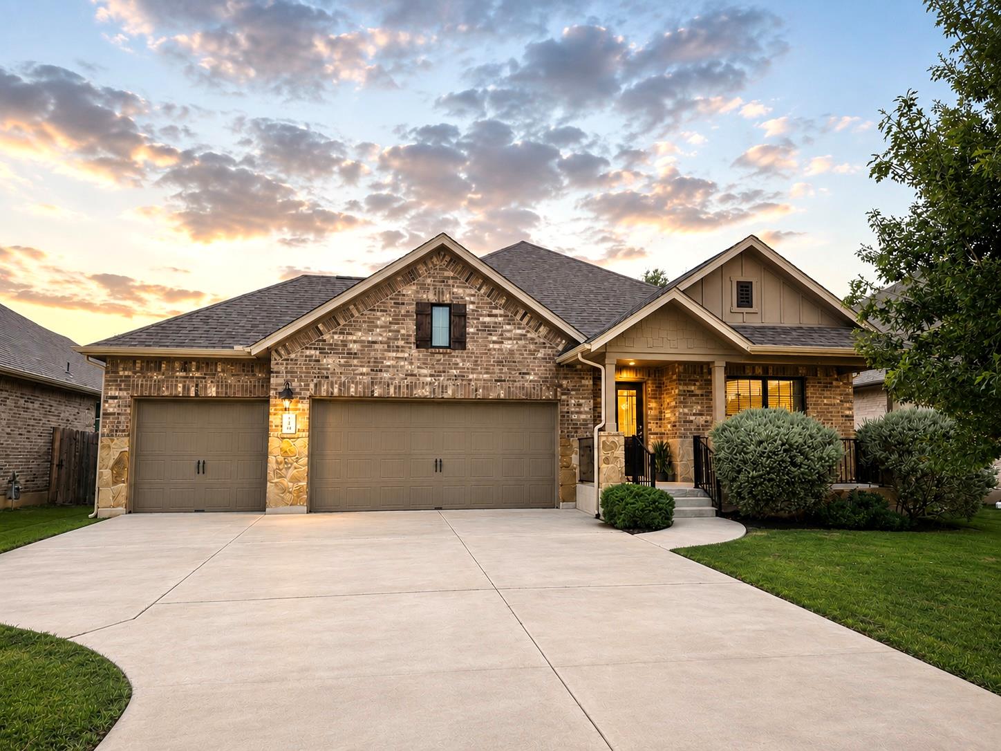 Brick house at dusk with a broad driveway, three-car garage, and covered entry.