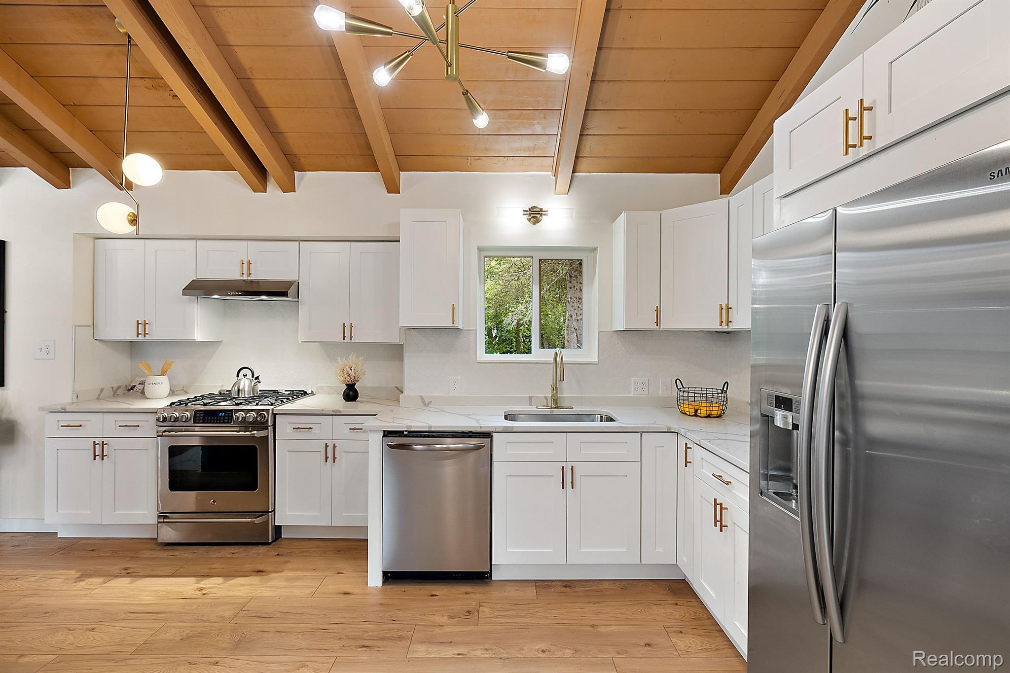 Kitchen with white cabinets, stainless steel appliances, and an exposed wood-beam ceiling.