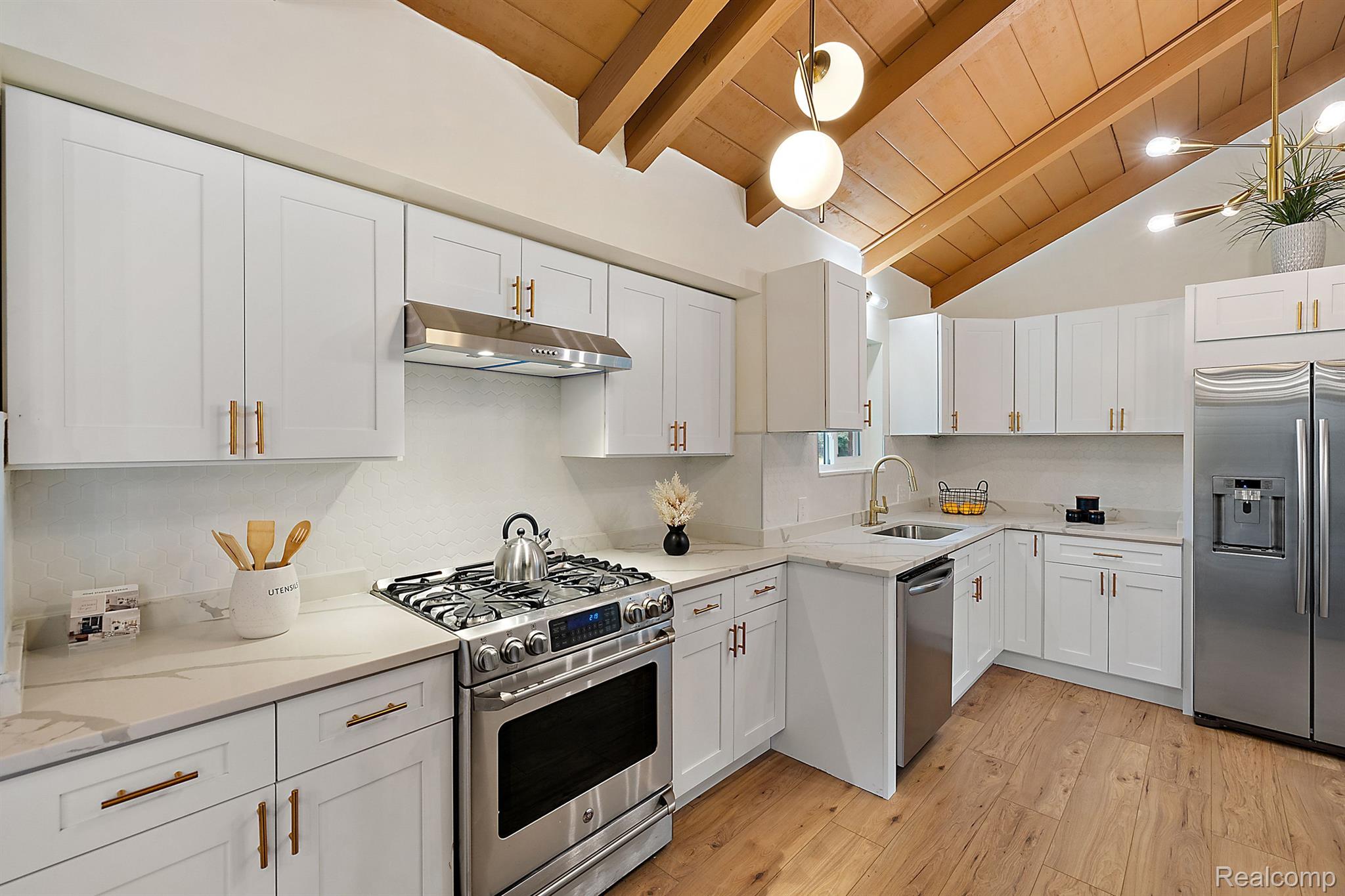 Kitchen with white cabinets, stainless steel appliances, and a vaulted wood ceiling.
