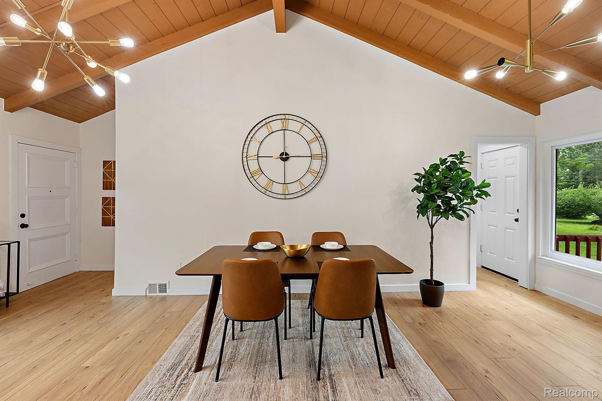 Furnished dining room with a vaulted wood ceiling, large wall clock, and table set for four.