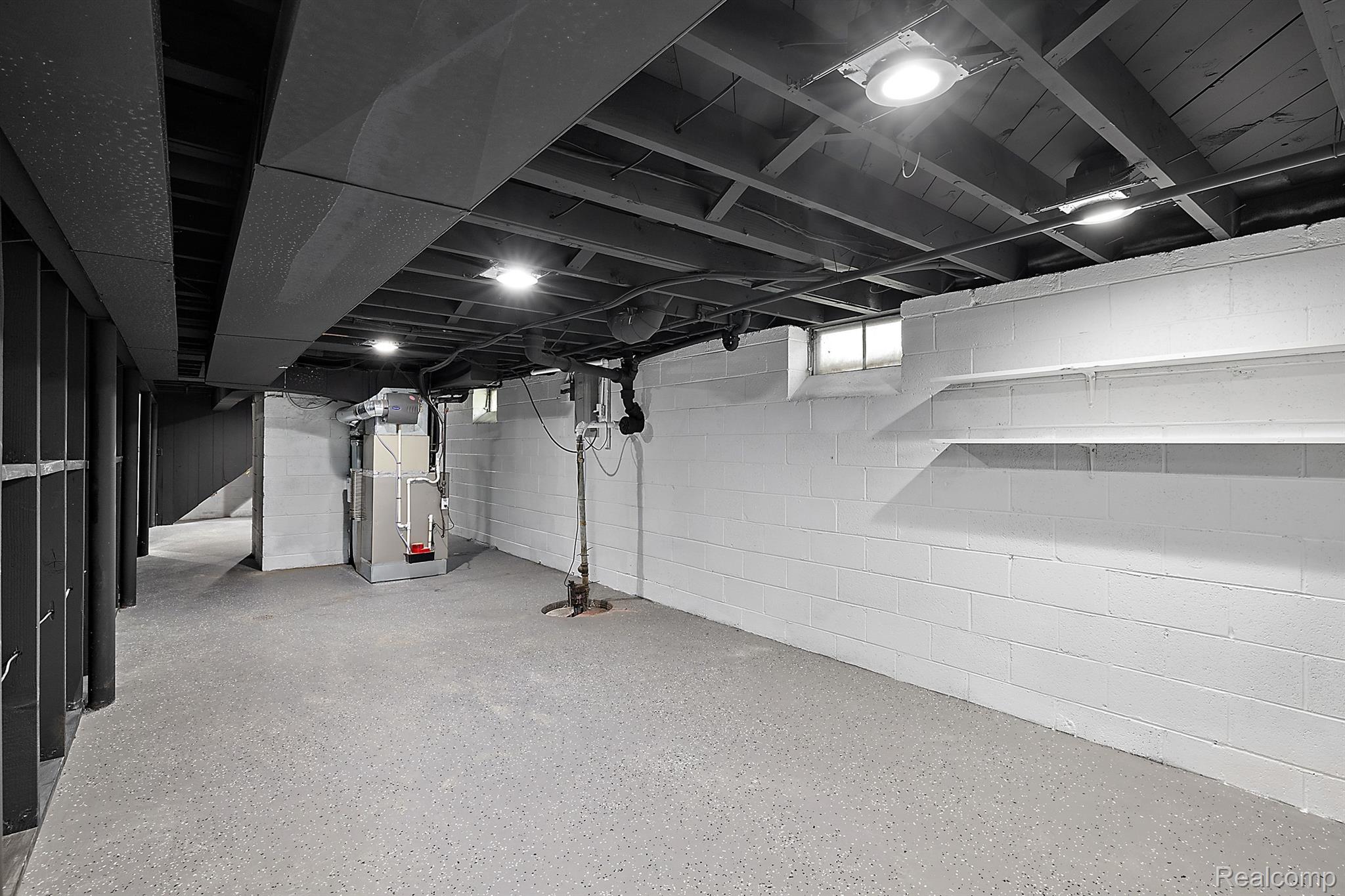 Unfinished basement with exposed ceiling joists, block walls, and mechanical equipment.