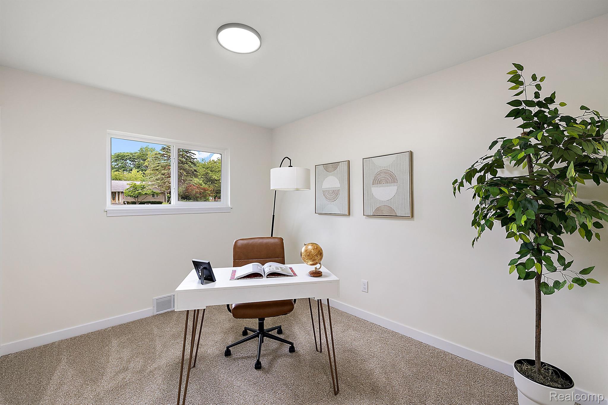 Furnished home office with a white desk, brown swivel chair, and large potted tree.