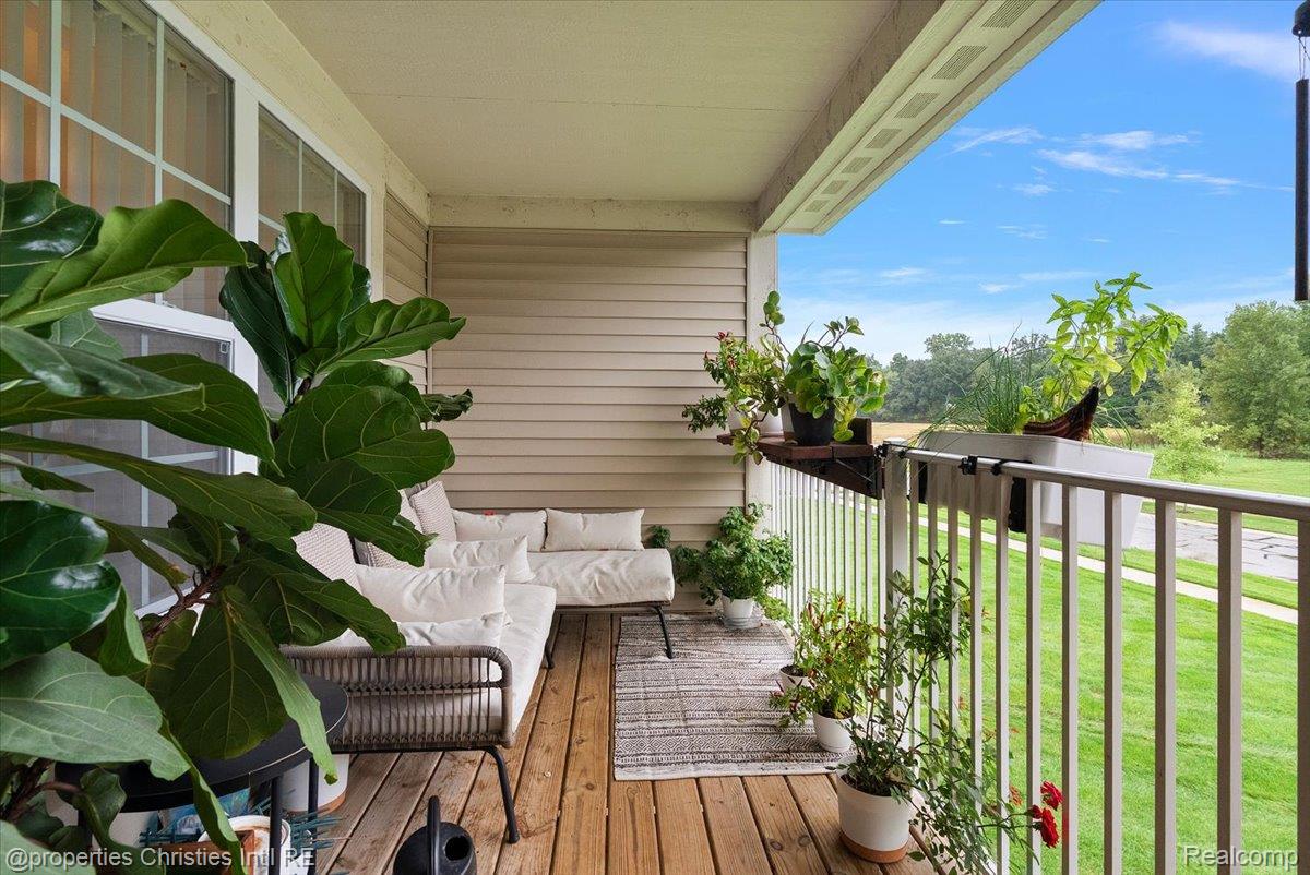 Covered porch with cushioned seating and potted plants overlooking a green lawn.