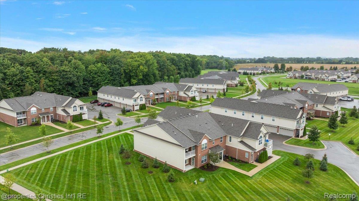 Aerial view of a residential neighborhood with two-story homes, curved streets, and a wooded edge.