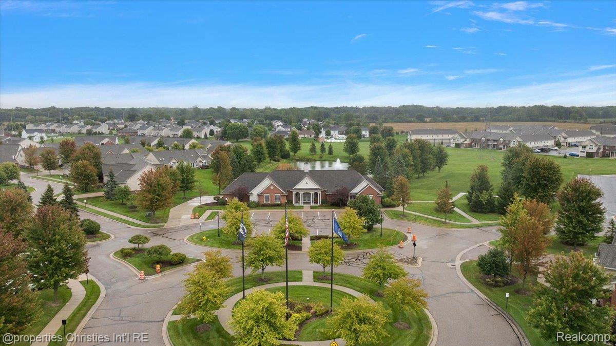 Aerial view of a residential community with a brick clubhouse and landscaped entrance.