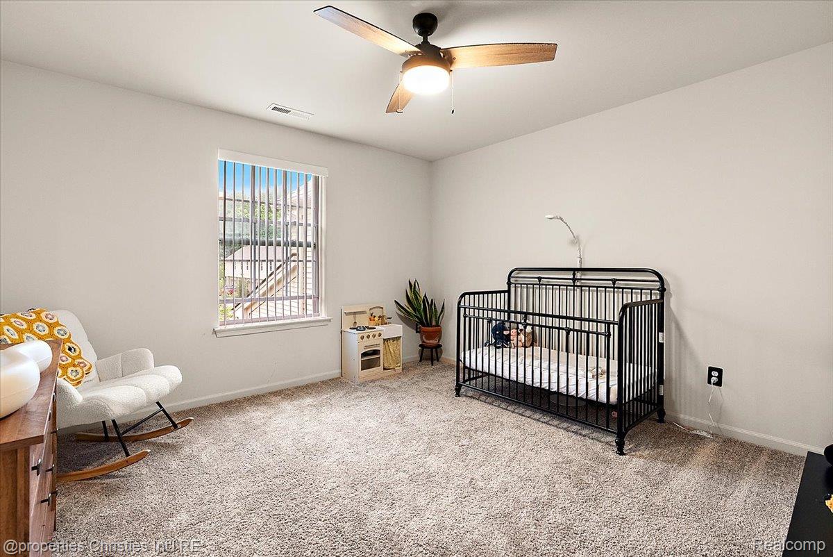 Nursery with a black metal crib, rocking chair, and small play kitchen.