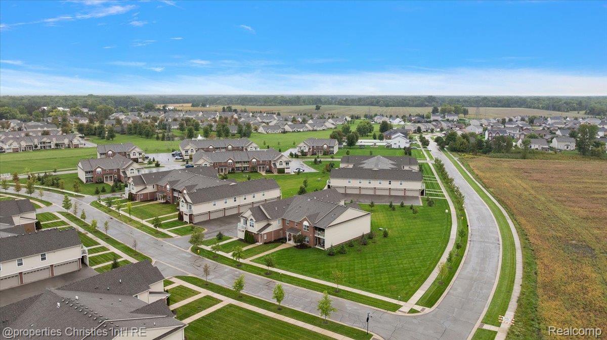 Aerial view of a suburban neighborhood with homes along a curving road beside open farmland.