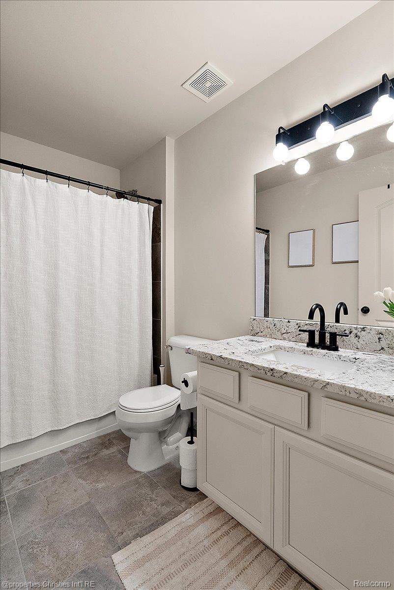 Bathroom with a white paneled vanity, speckled stone countertop, and black faucet.