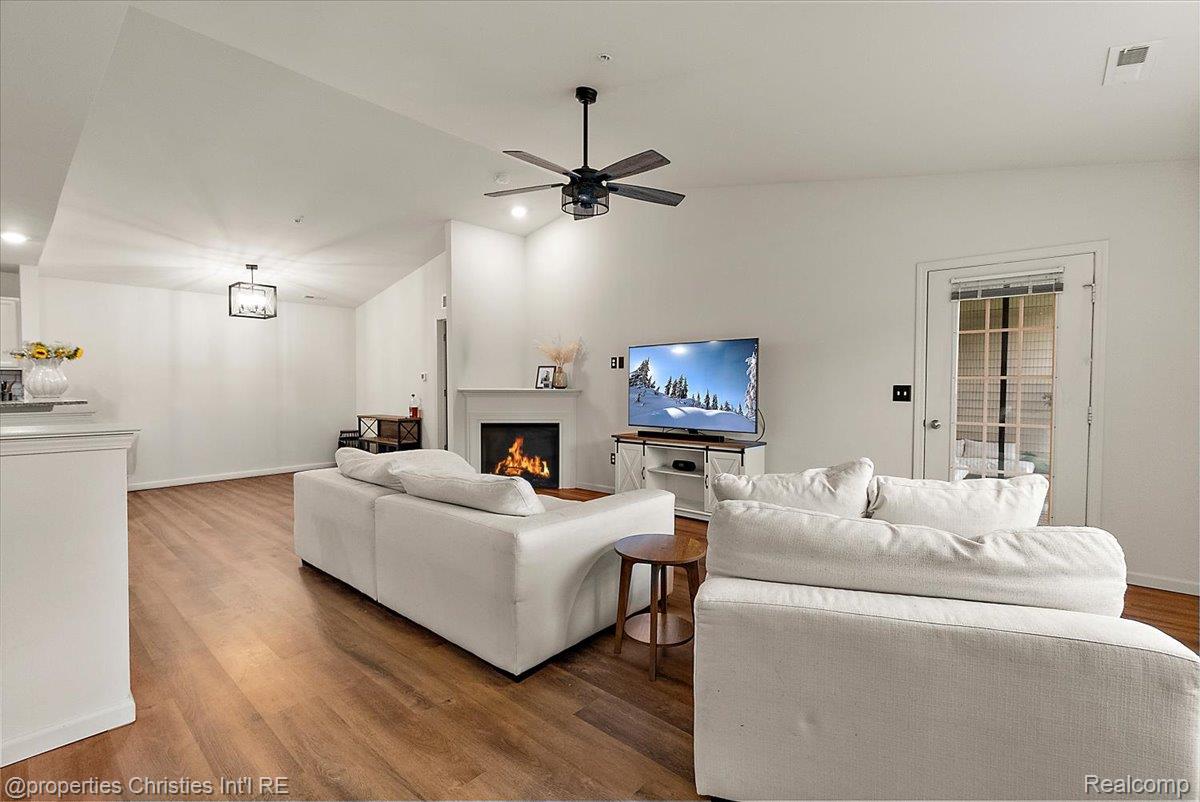 Living room with white sofas, a fireplace, and wood floors.
