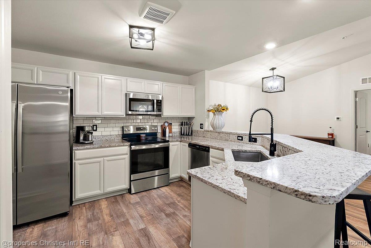 Updated kitchen with white cabinets, stainless appliances, and a large granite peninsula sink.