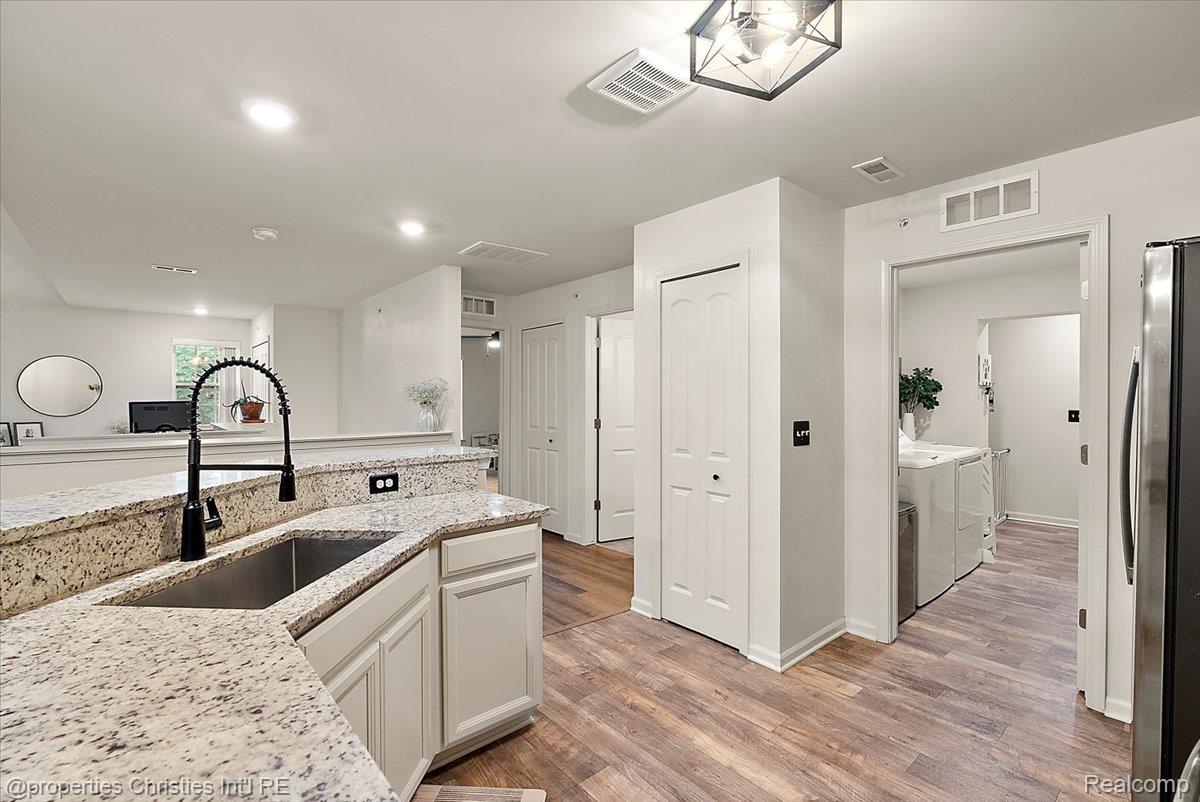 Kitchen with granite counters, white cabinetry, black faucet, and laundry area visible through doorway.