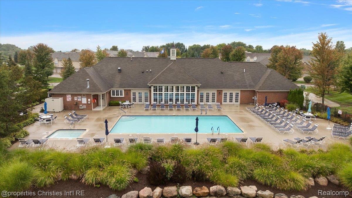 Community pool and brick clubhouse, with rows of lounge chairs and autumn trees.