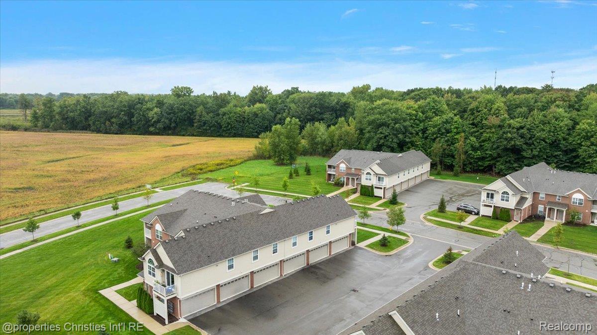Aerial view of townhouse-style homes beside a broad field and tree line.