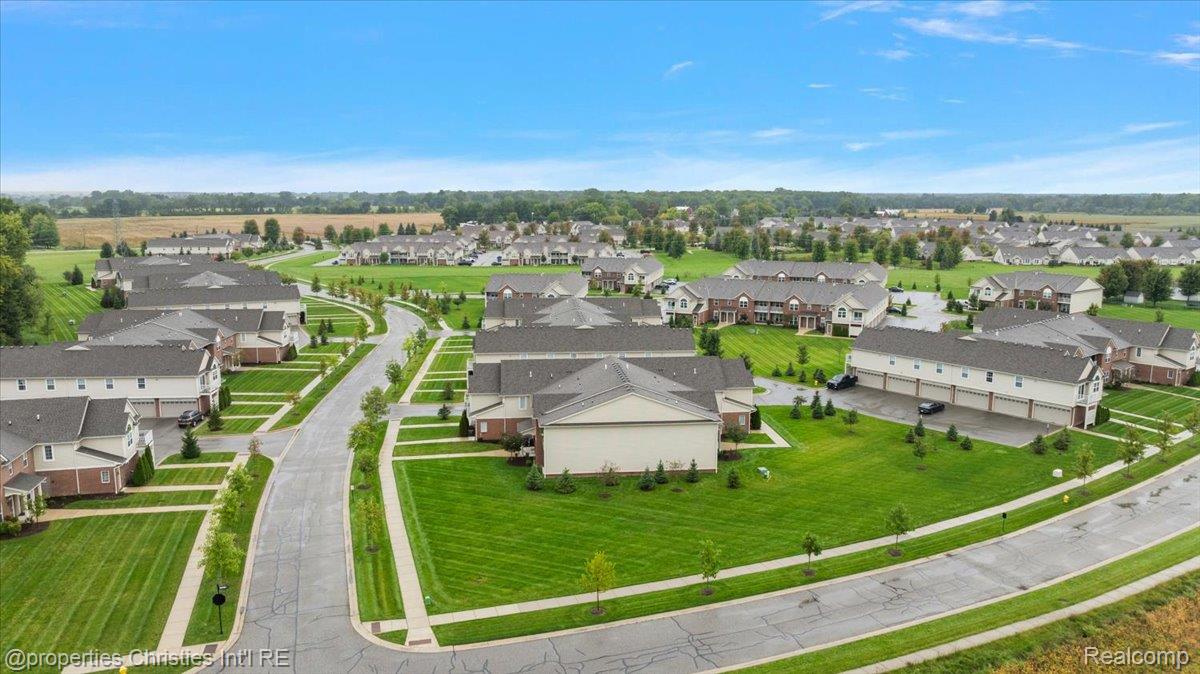 Aerial view of a subdivision with rows of homes, green lawns, and curving streets.