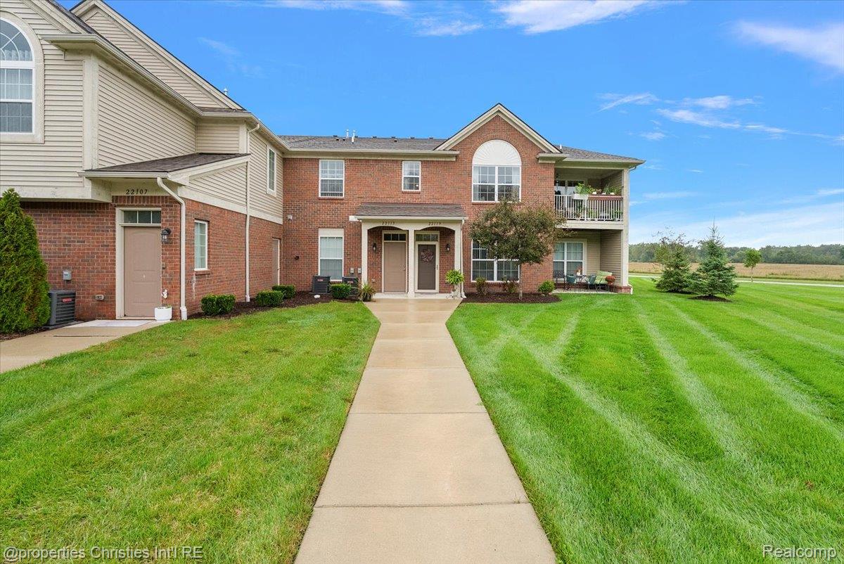 Two-story brick residence with a second-floor balcony and a walkway across the lawn.