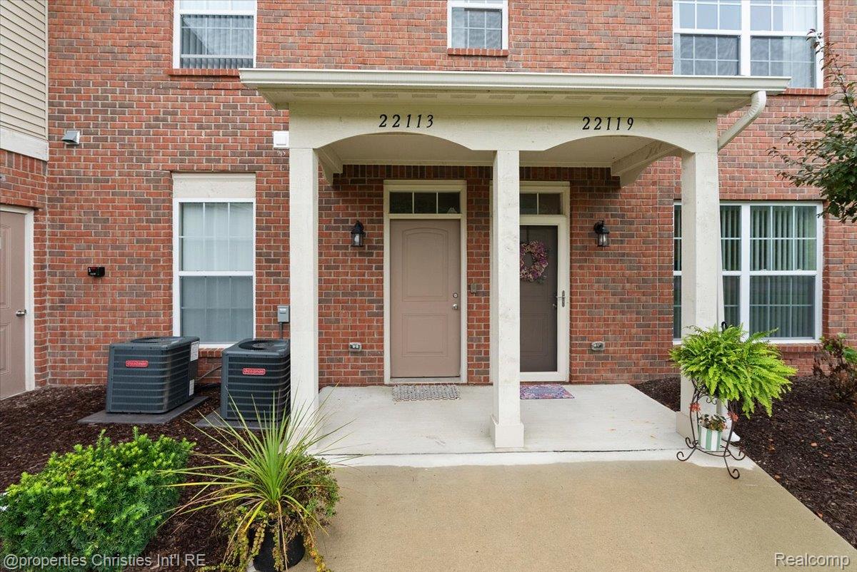 Brick residence entrance marked 22113, with a covered porch, concrete walkway, and landscaped beds.