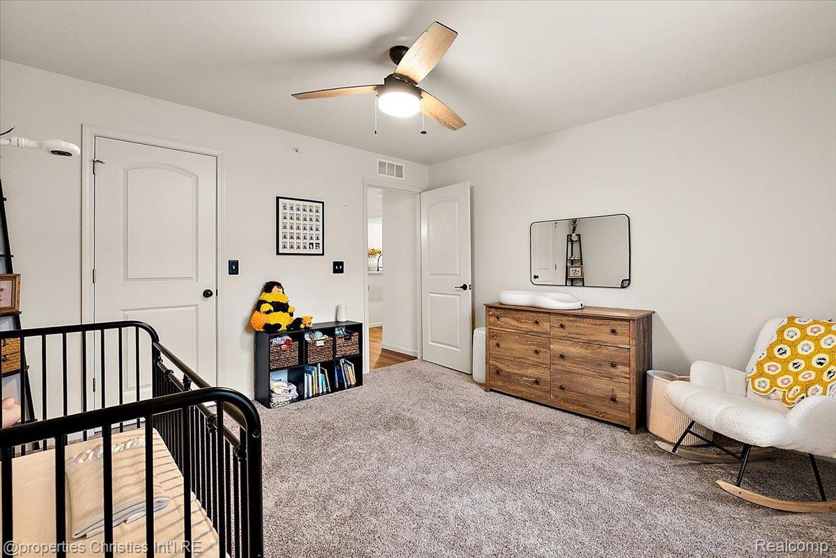 Nursery with a black crib, wooden changing dresser, and white rocking chair with a yellow cushion.