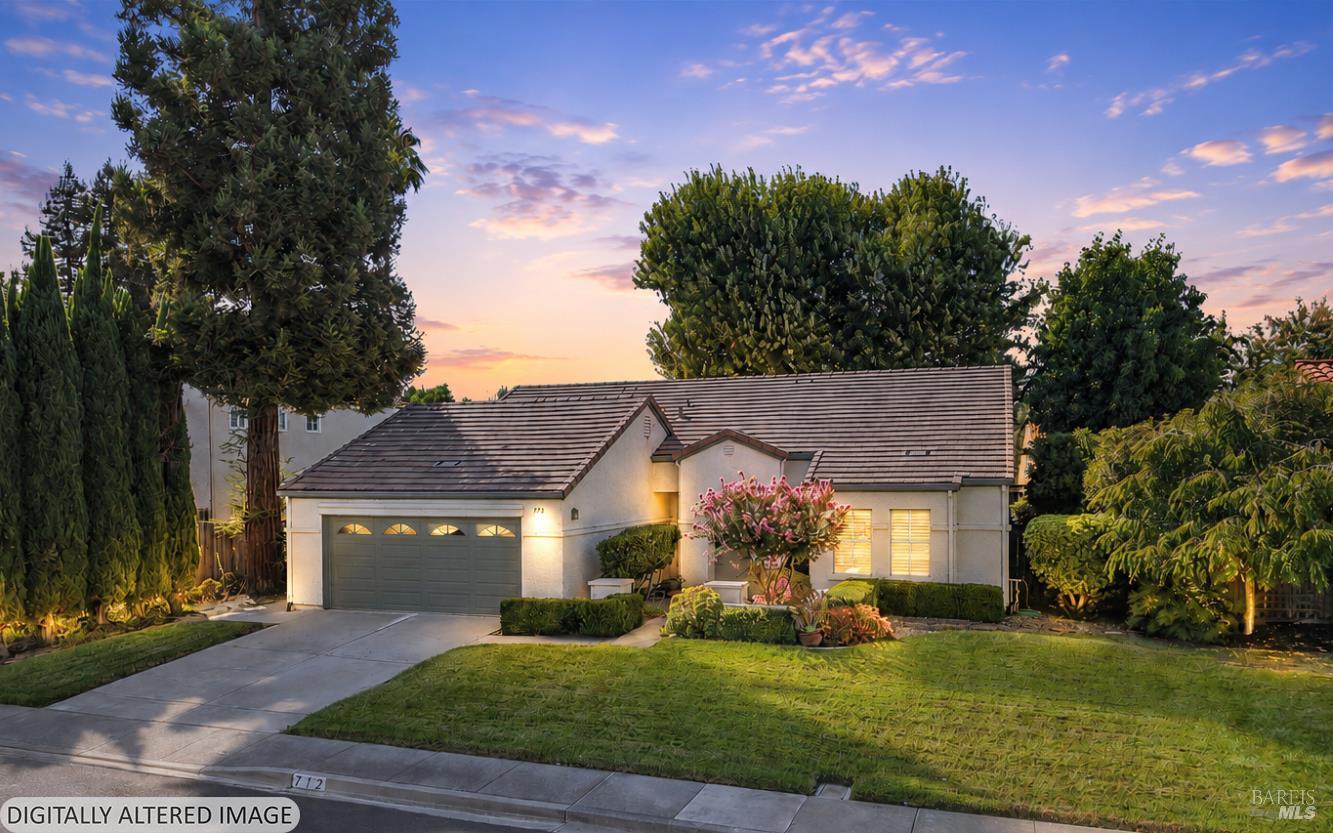 Single-story home with a two-car garage and landscaped front yard at dusk.