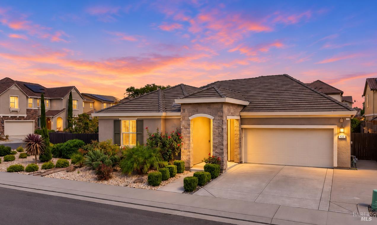 Single-story home with a stone entry, two-car garage, and landscaped front yard at sunset.