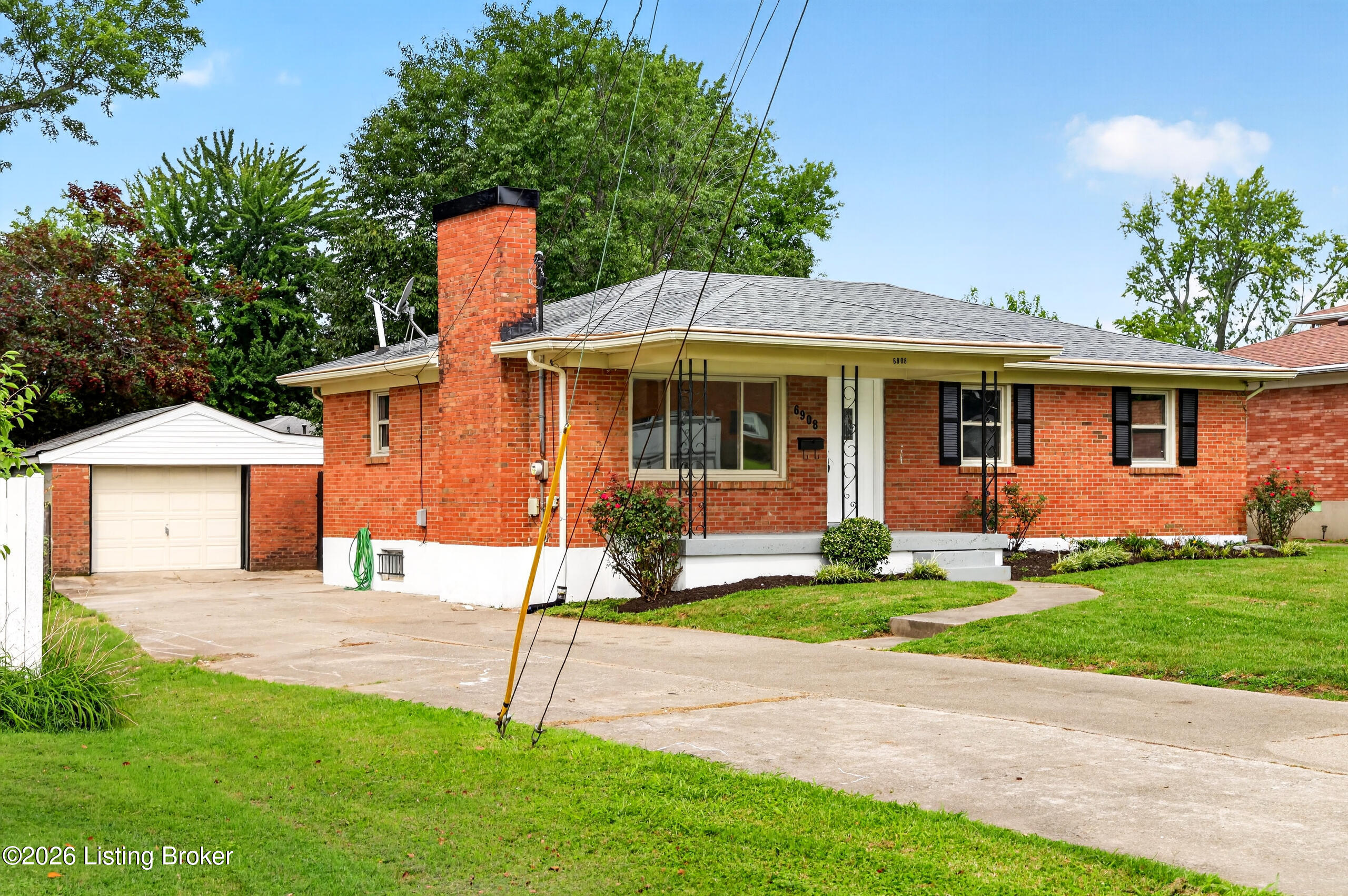 Red-brick ranch house with an attached garage, gray roof, and small covered front porch.