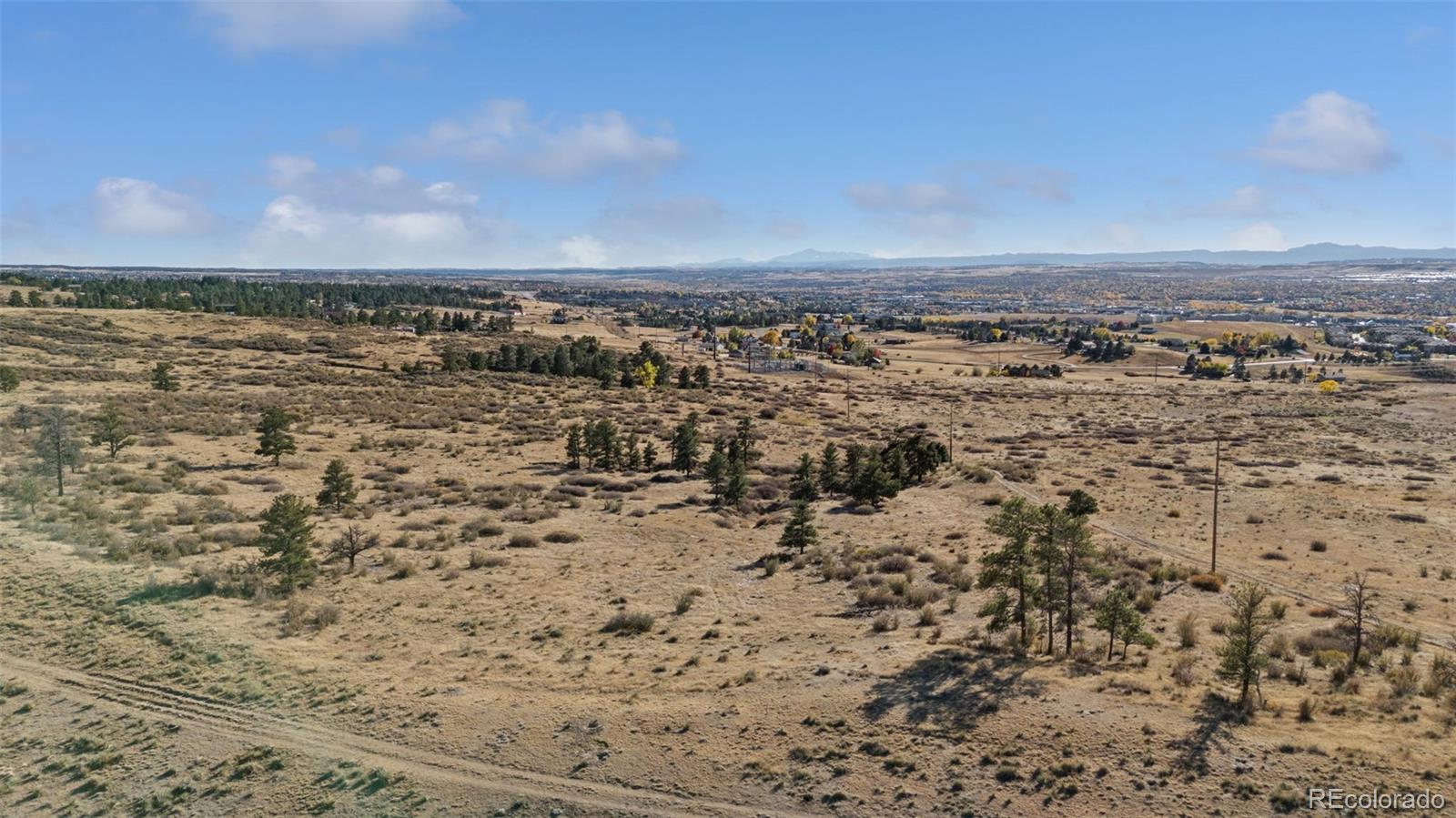 Open acreage with scattered pines and distant mountain views near Parker, Colorado.