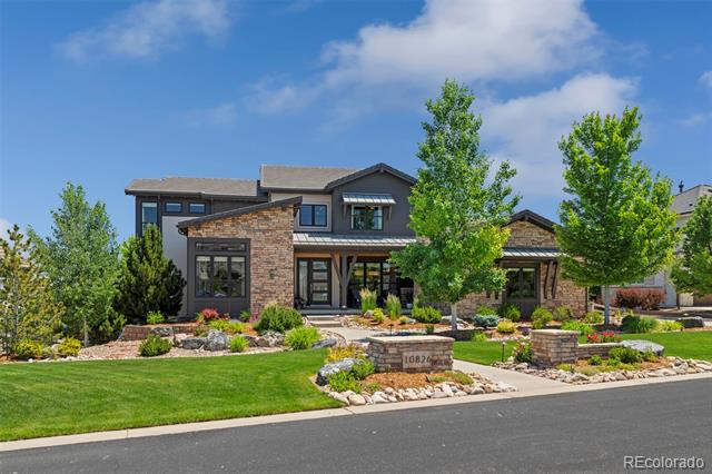 Two-story modern home with stone accents, landscaped yard, and a stone entry marker.