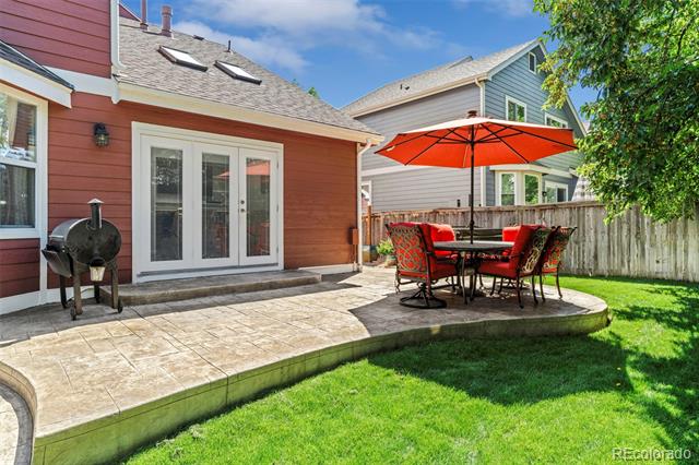 Backyard patio with a stone-paved terrace, red umbrella, and outdoor dining set.