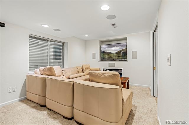 Basement family room with a beige sectional, carpeted floor, and wall-mounted television.