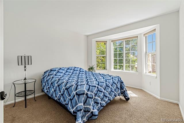 Bedroom with a blue geometric comforter and a curved bay window overlooking trees.
