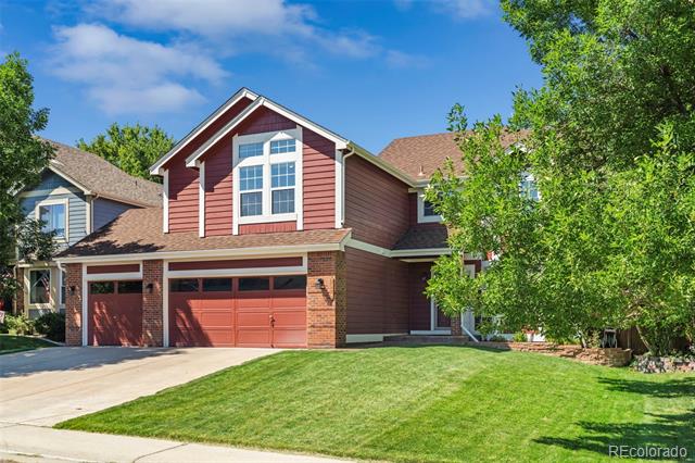 Two-story red-sided and brick house with a double garage and broad front lawn.