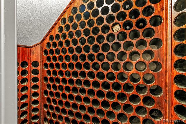 Wine cellar with reddish wood walls and rows of circular bottle cubbies.