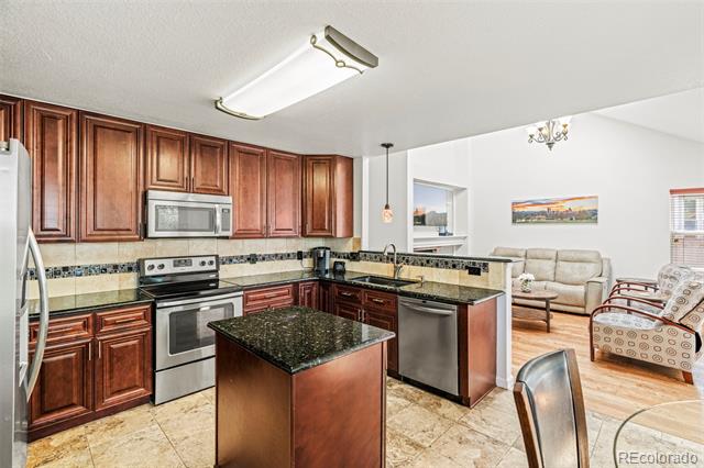 Kitchen with dark wood cabinets, granite counters, central island, and adjoining living room.