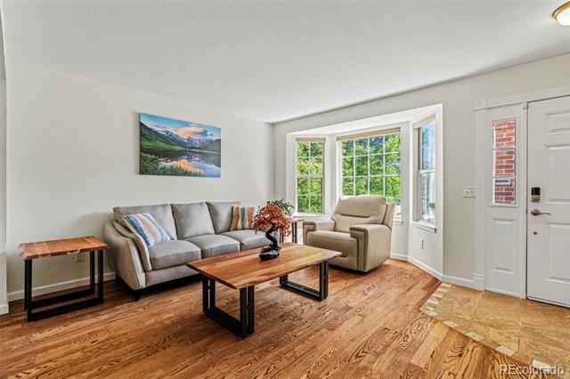 Living room with gray sofa, beige armchair, wooden coffee table, and large windows.