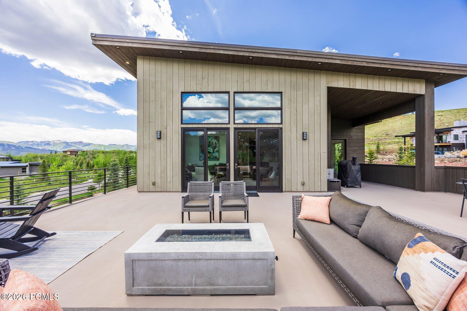 Modern mountain home with a furnished terrace, fire table, and mountain views.