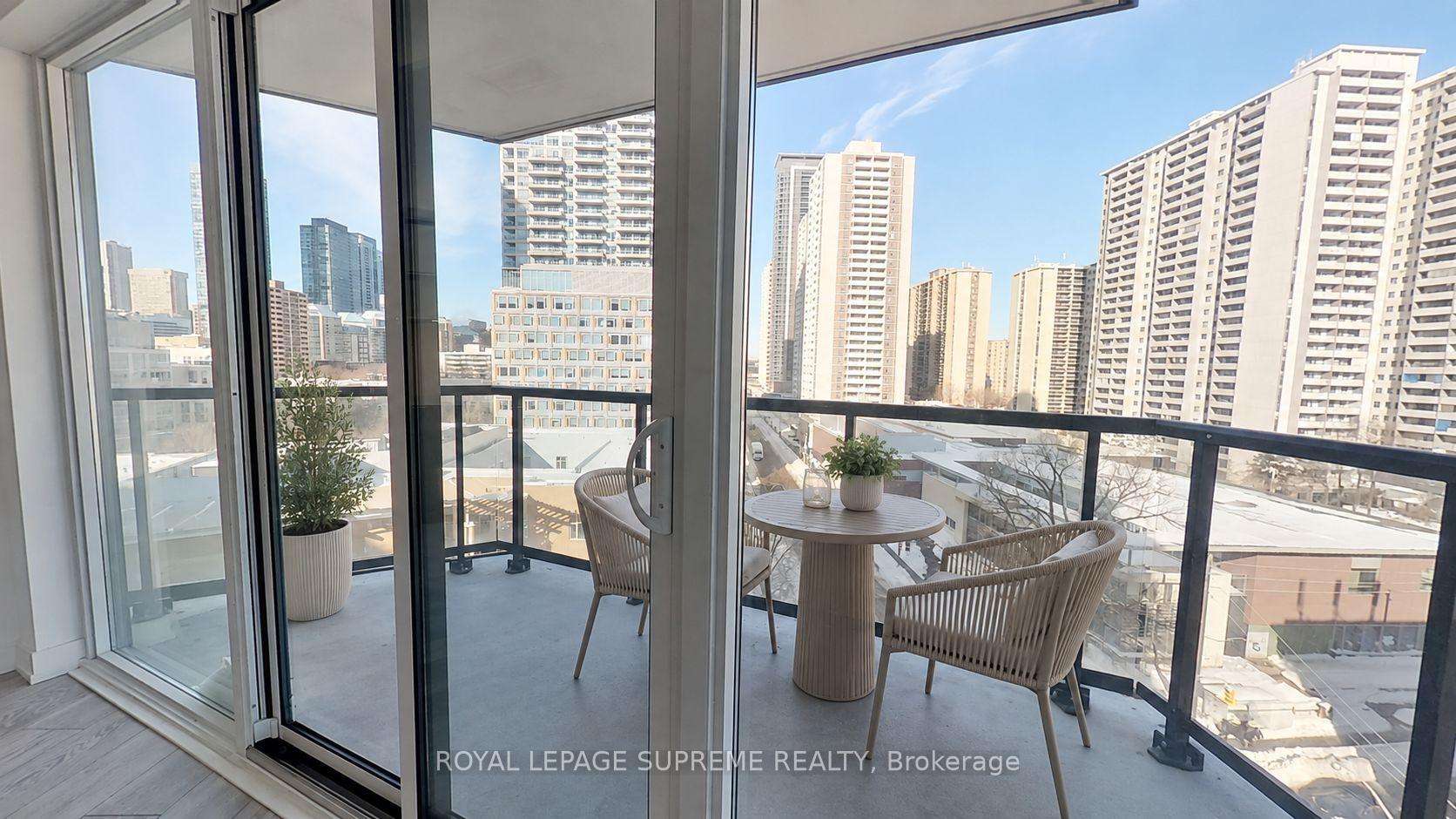 Condo balcony with a round table and woven chairs overlooking Toronto high-rises.