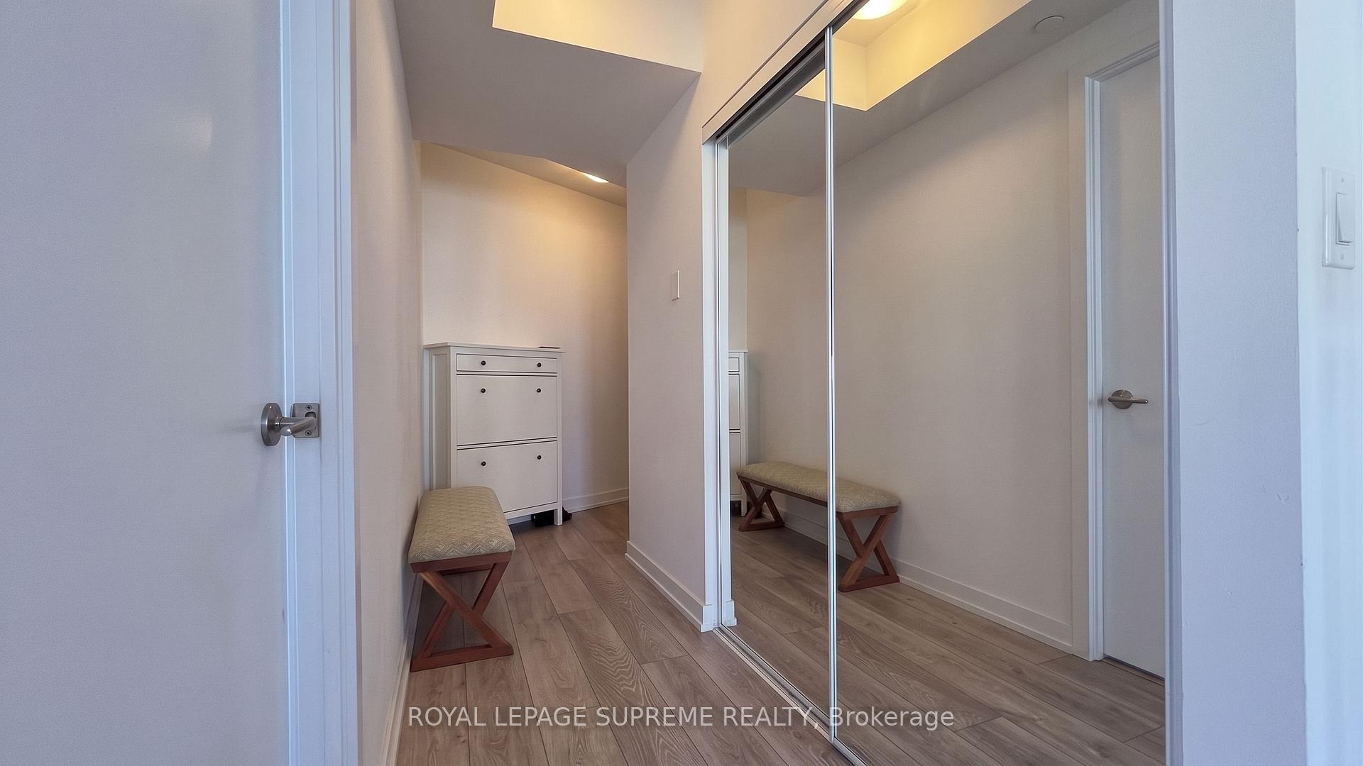 Condo entry hallway with mirrored closet doors, a cushioned bench, and a white shoe cabinet.
