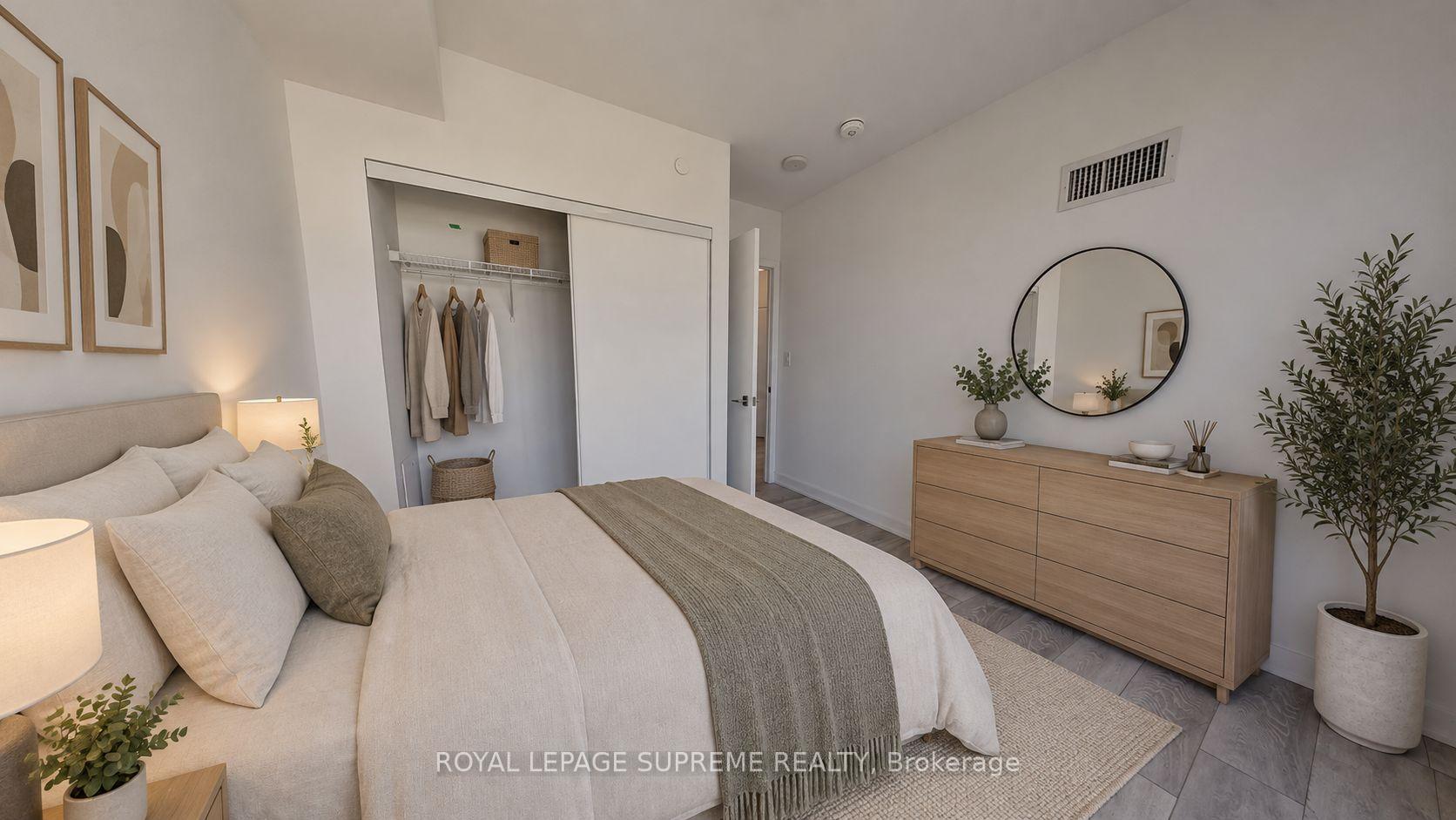 Staged bedroom with a neutral bed, open closet, wood dresser, and round wall mirror.