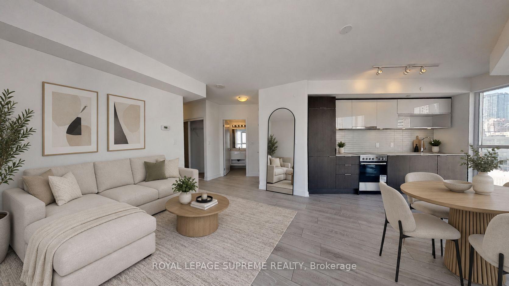 Staged condo living and dining area with a sectional sofa, modern kitchen, and large windows.