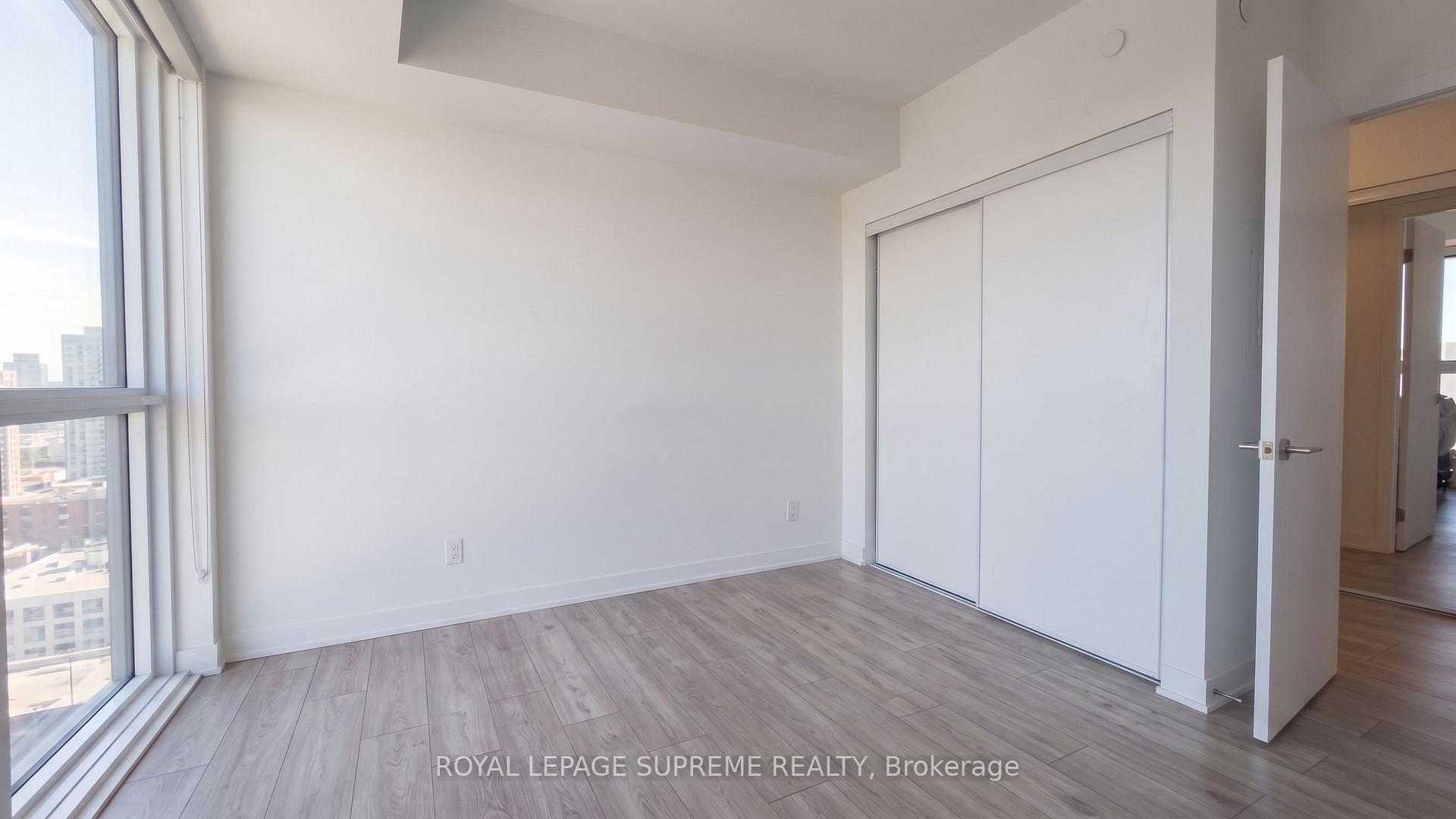 Vacant bedroom with floor-to-ceiling windows, a sliding-door closet, and light gray wood-look flooring.