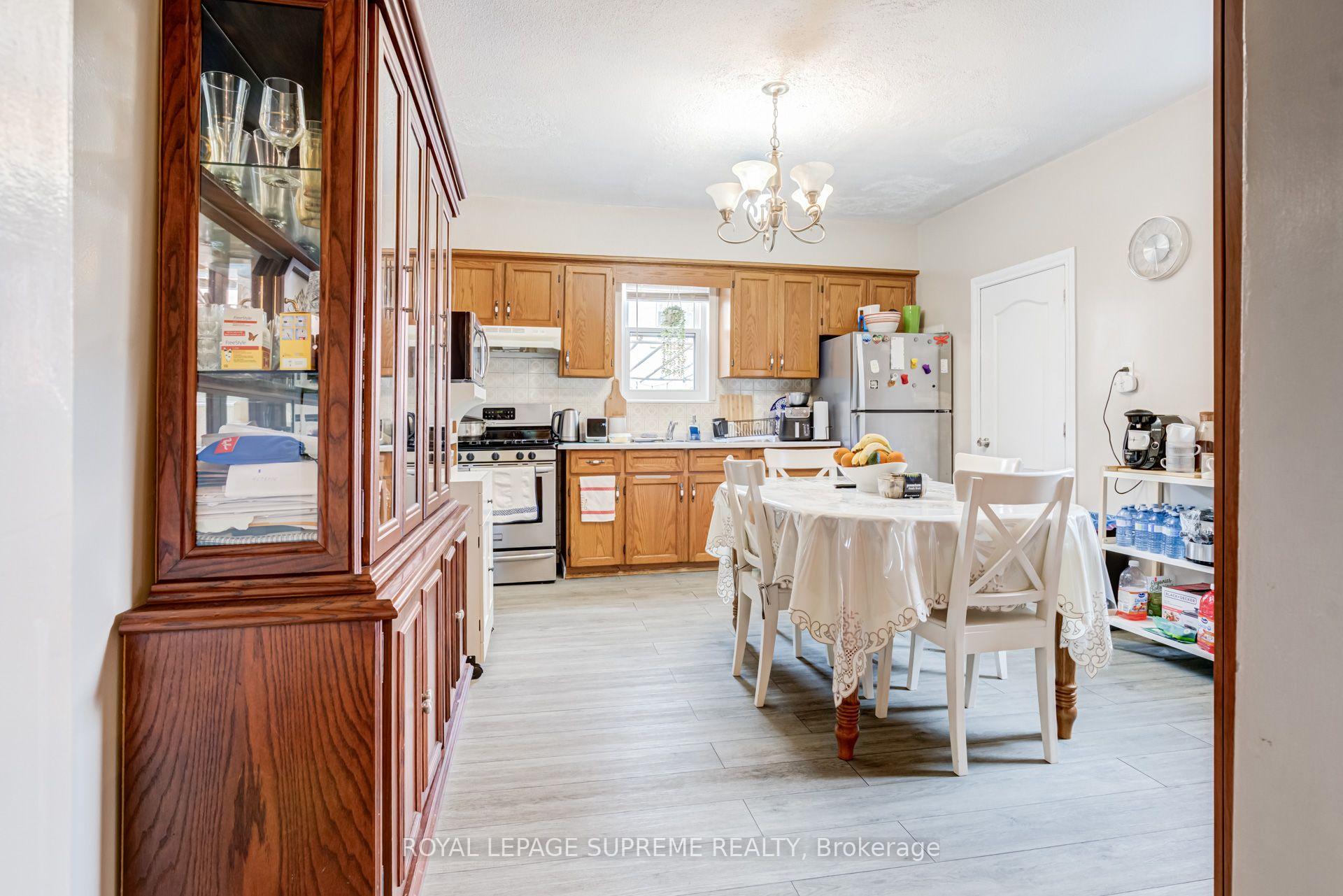 Kitchen and dining area with honey-toned cabinets, a white table, and a glass-front wood display cabinet.