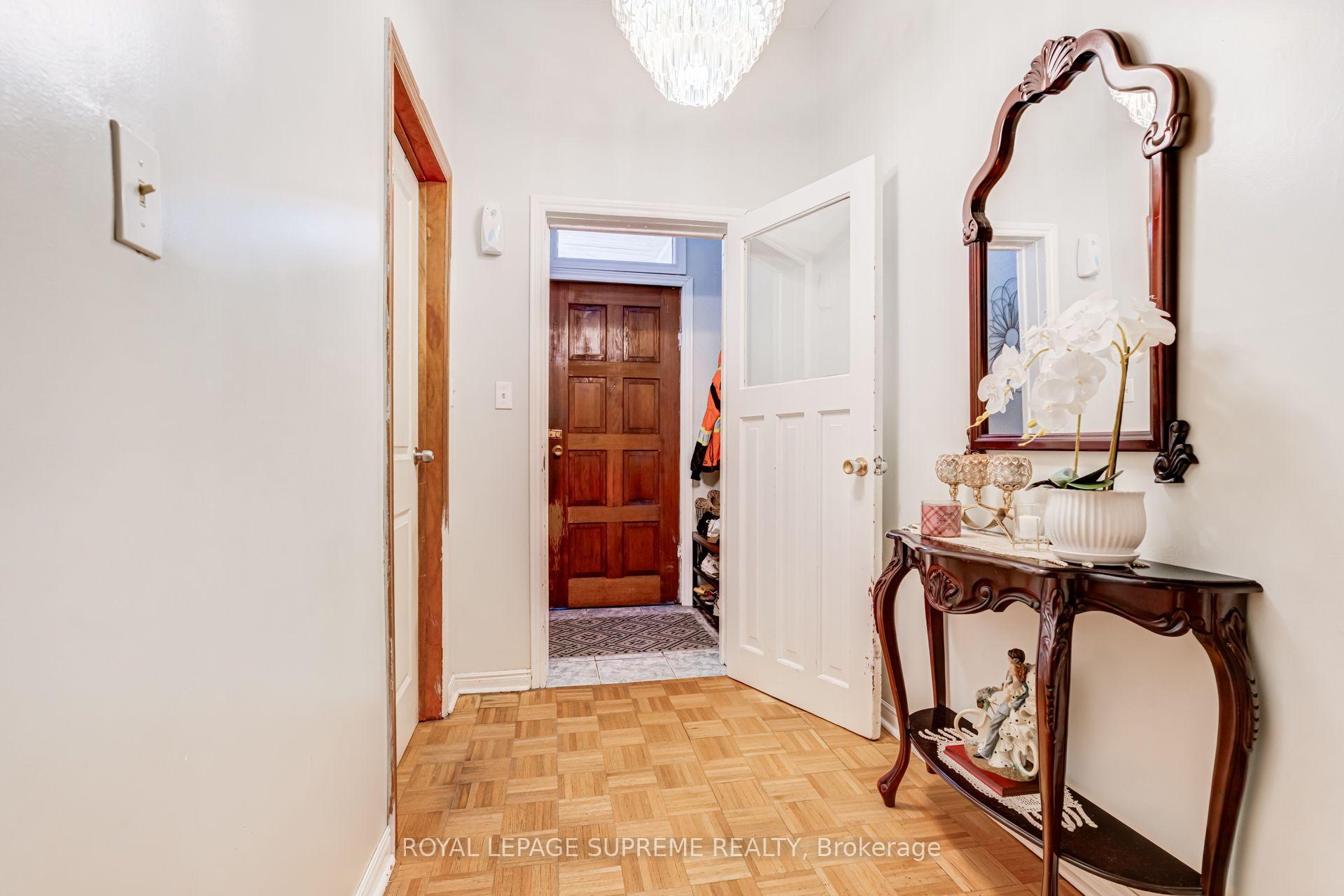 Entry hall with parquet flooring, a dark wood front door, and an ornate mirror above a console table.