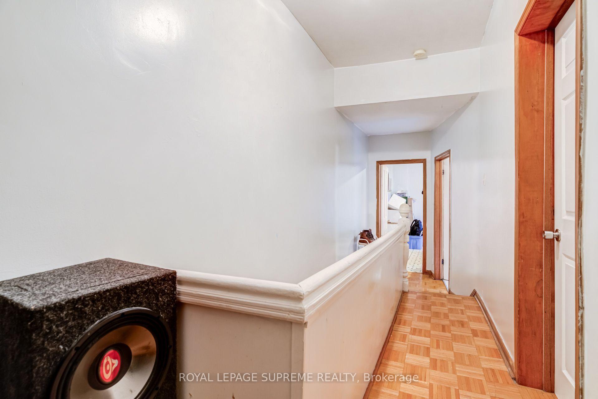 Narrow hallway with parquet flooring, wood-trimmed doorways, and a half-height wall.