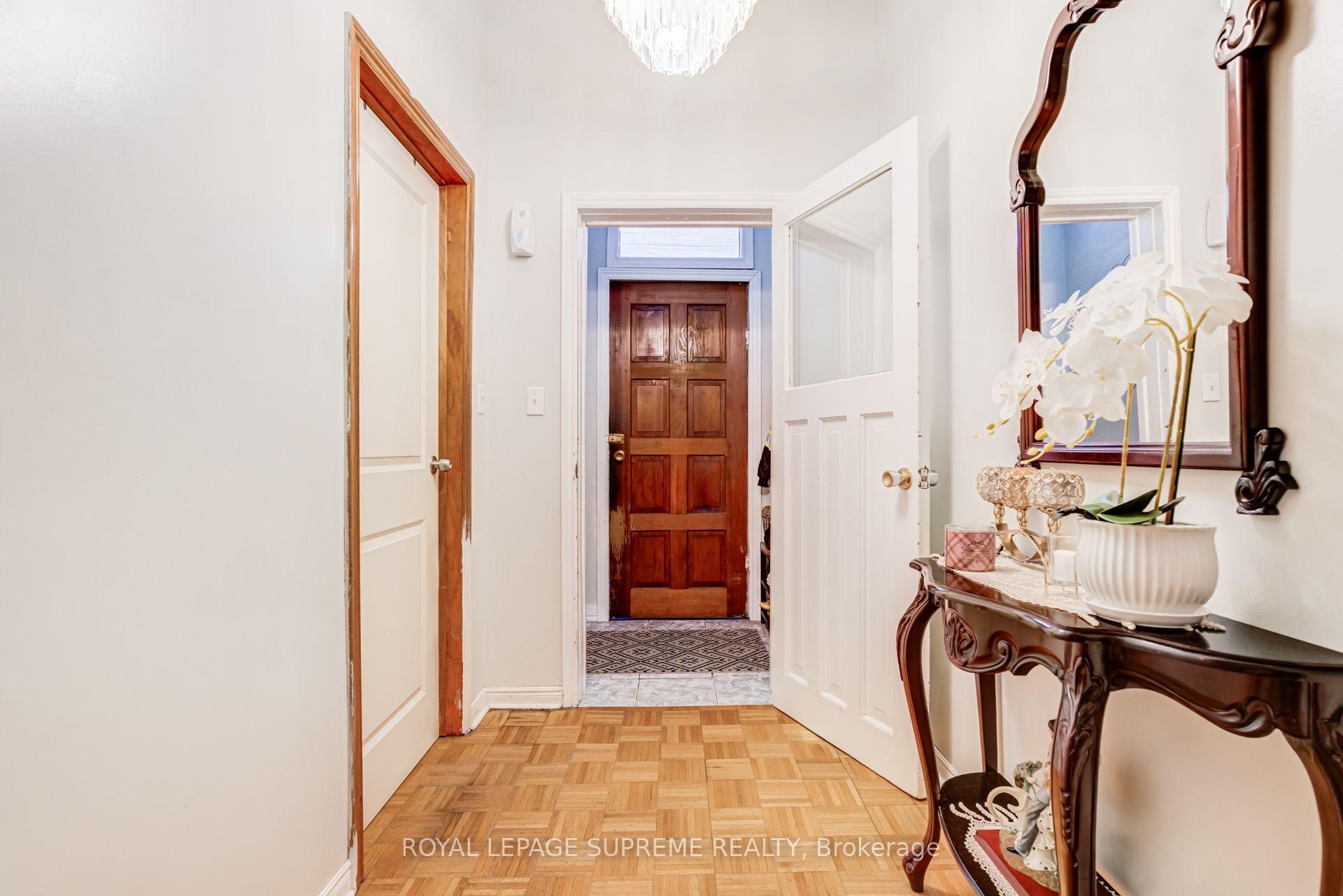 Entry hallway with a dark wood front door, parquet flooring, and a console table topped with white orchids.