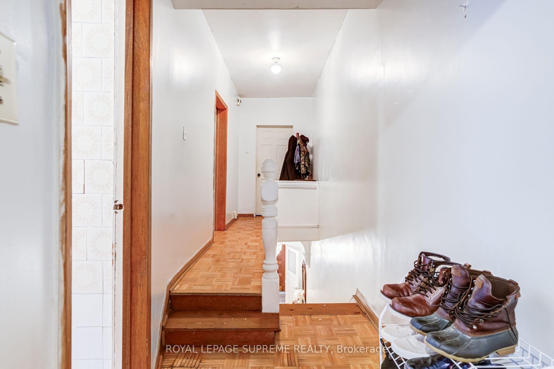 Upstairs hallway with parquet flooring, wooden steps, and a shoe rack beside the stairwell.