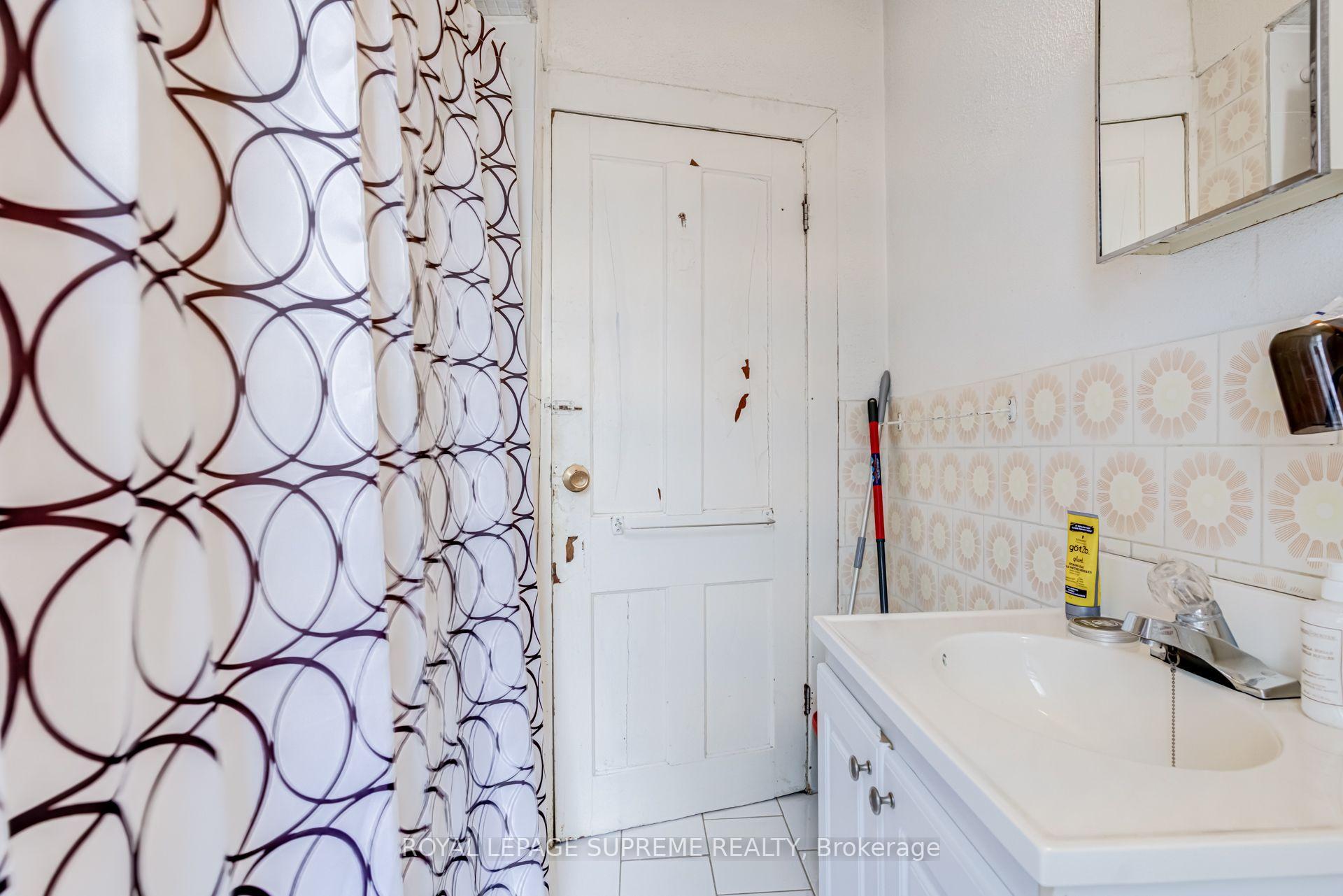 Bathroom with a white sink vanity, floral wall tiles, and a bold circular-patterned shower curtain.