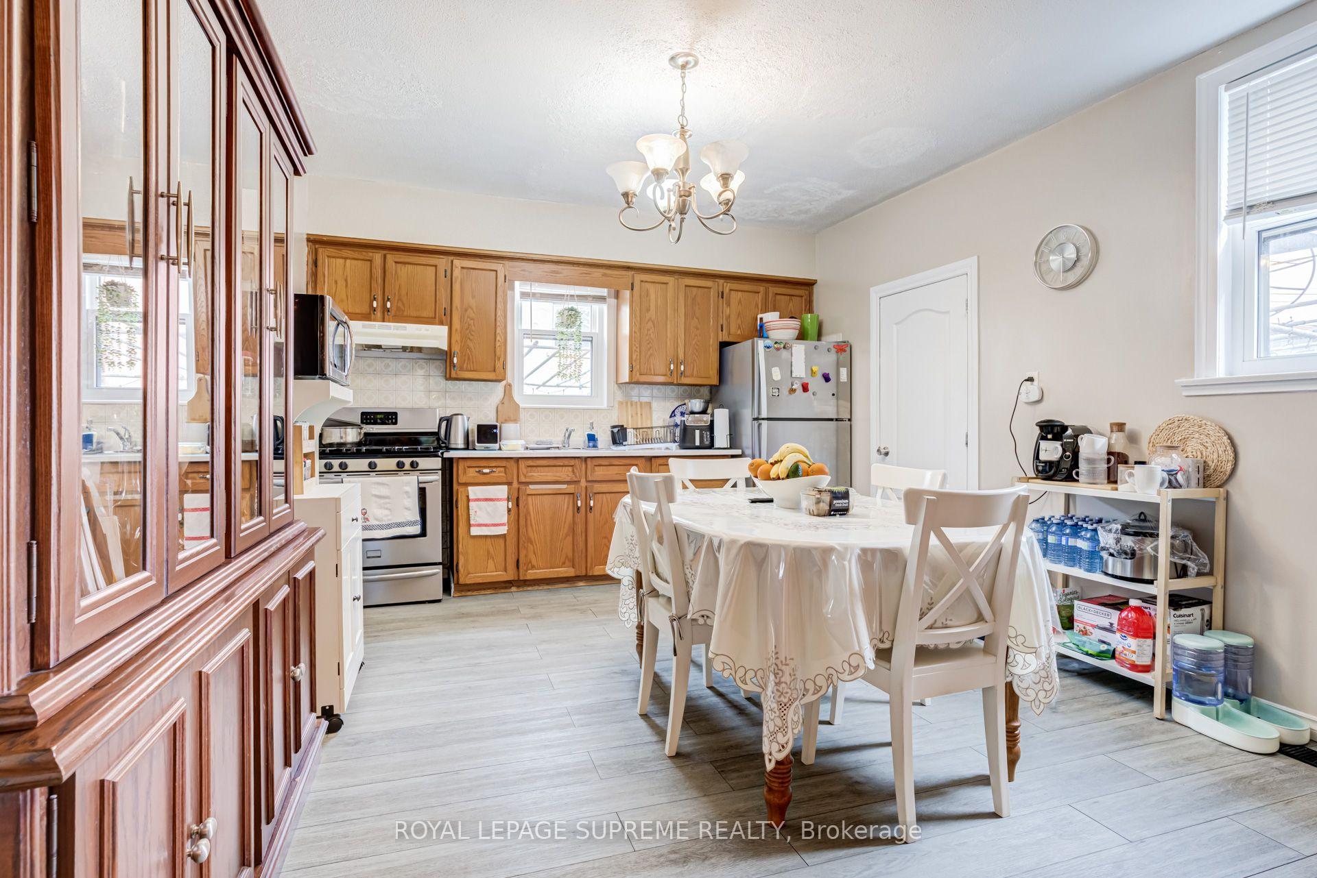 Kitchen and dining area with wood cabinets, stainless steel appliances, and a white dining table.