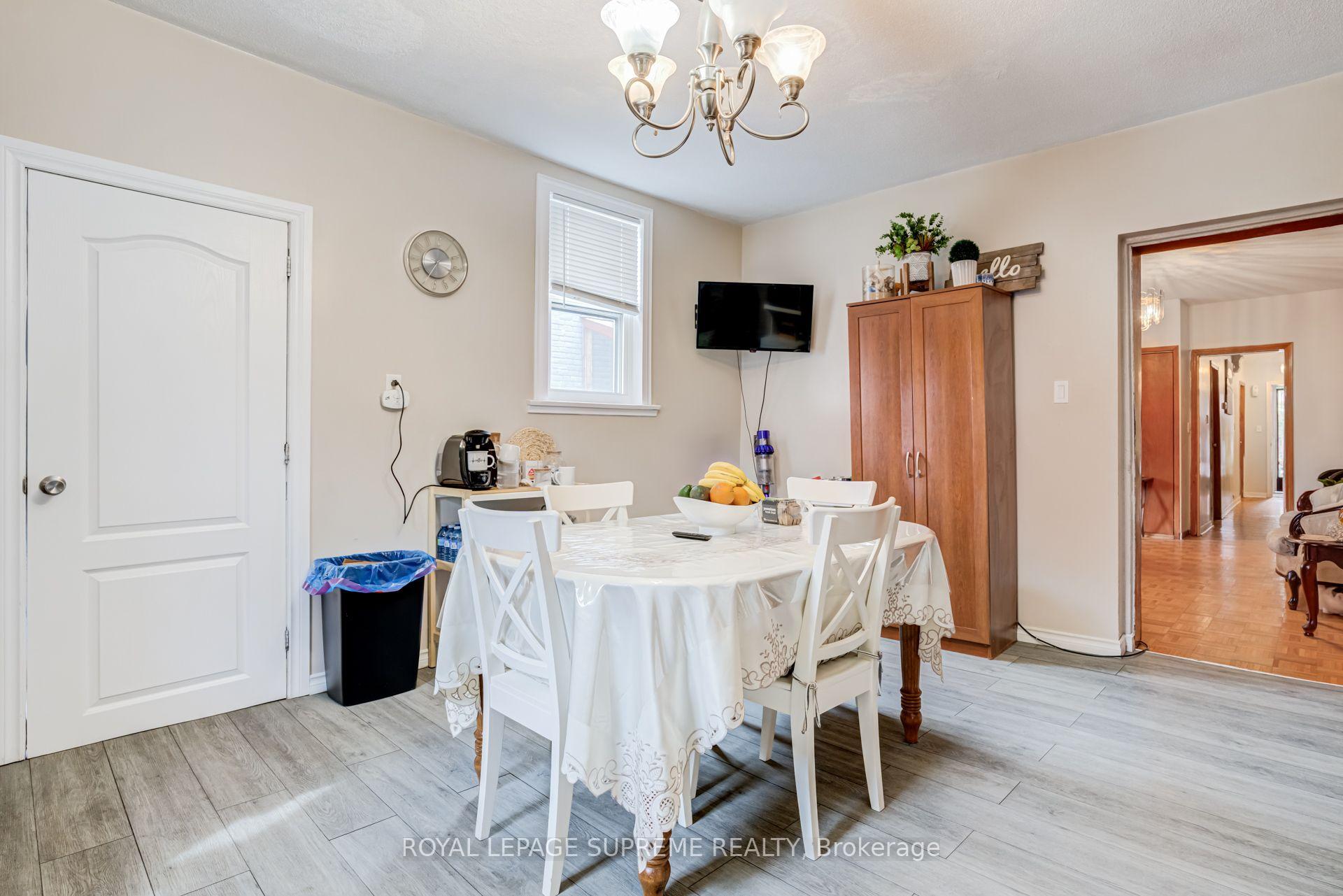 Dining room with a white table and chairs, wooden cabinet, and gray tile flooring.